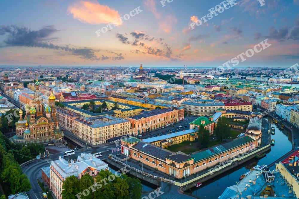 На снимке запечатлен Храм Спаса на Крови, яркий символ Санкт-Петербурга, окруженный зданиями исторического центра города. Канал Грибоедова и набережные добавляют композиции уникальной атмосферы. Утренний свет и нежные облака подчеркивают архитектурную гармонию и величие Петербурга. Это вид с высоты показывает, как город сочетает историю и красоту.